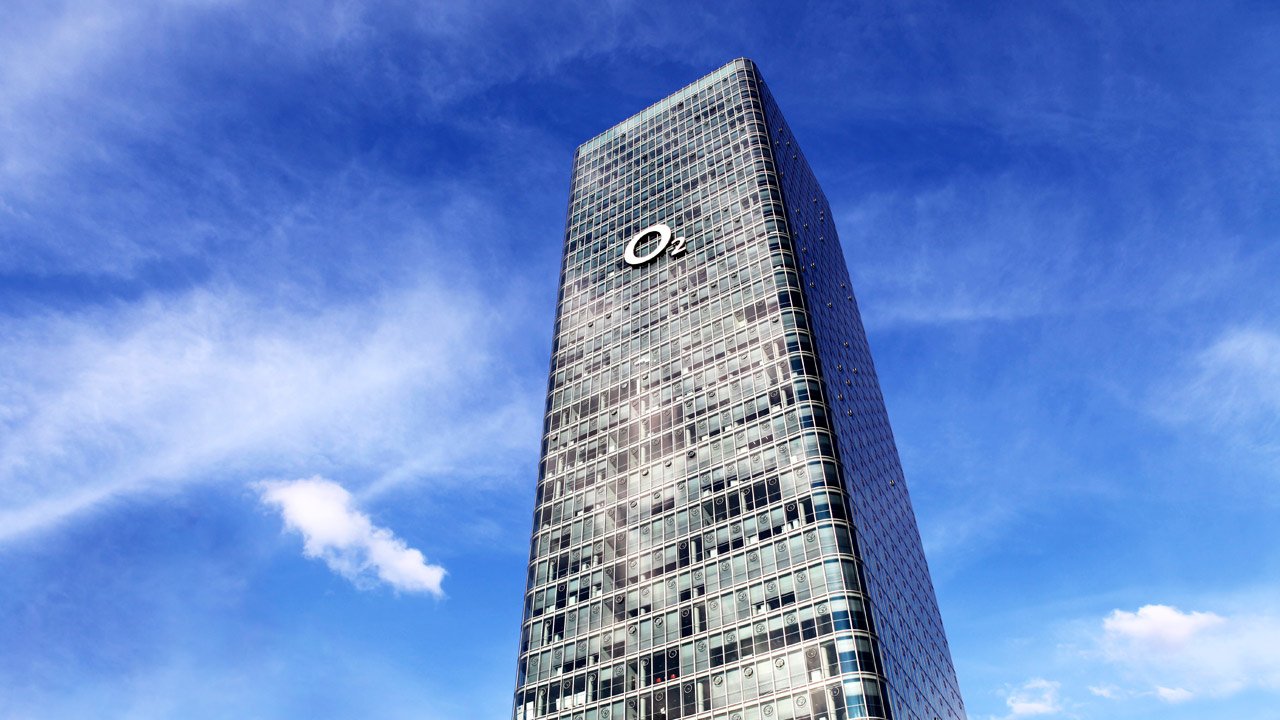 Der o2 Tower im Uptown München, von unten gegen den blauen Himmel fotografiert.